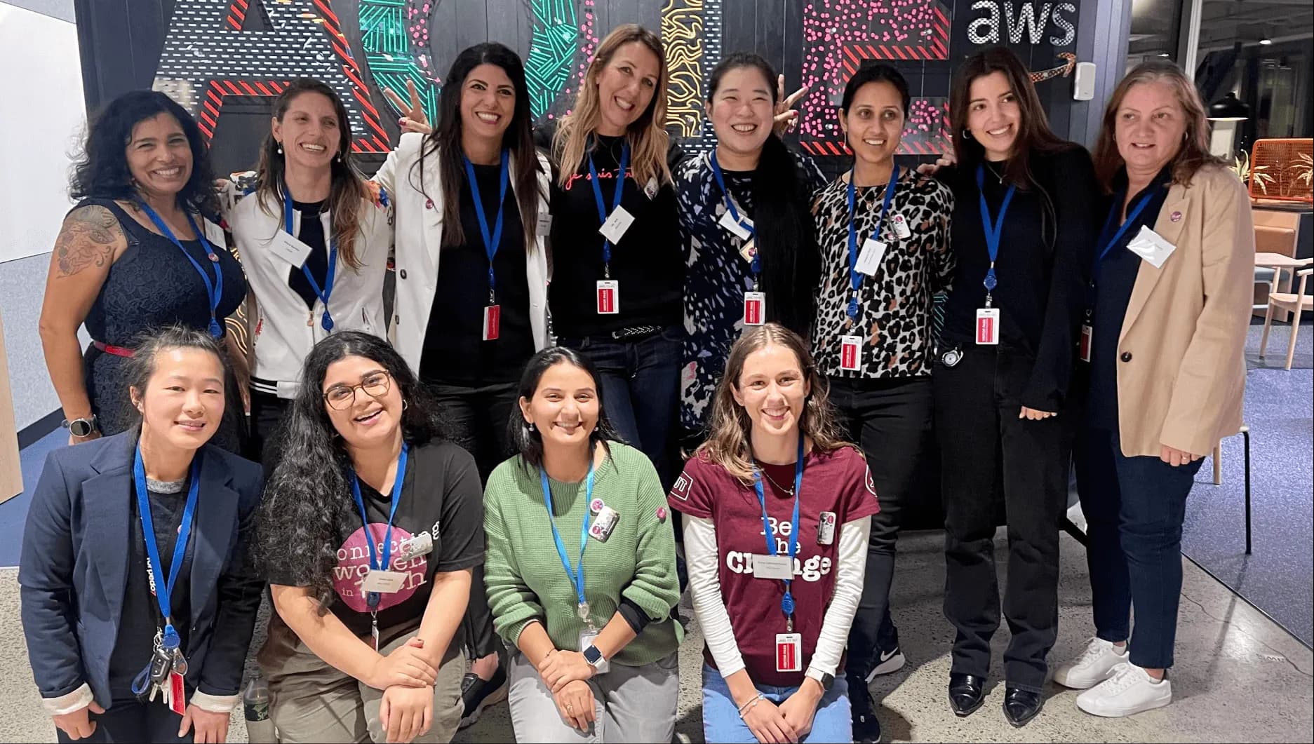 A group of smiling women wearing event lanyards at a She Sharp gathering.