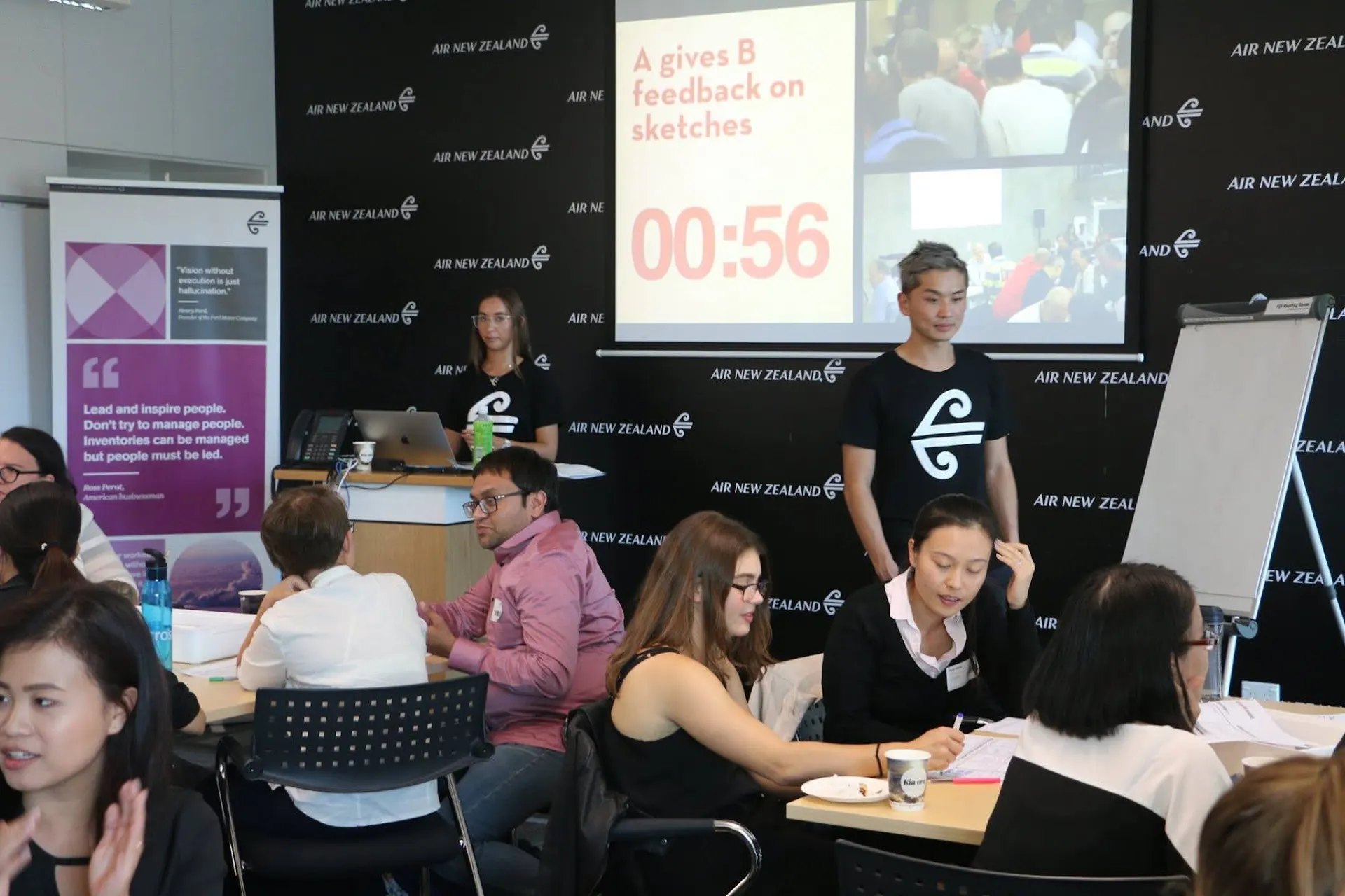 Two participants working together at a laptop during a She Sharp design-thinking workshop, with a countdown timer on the screen behind them.