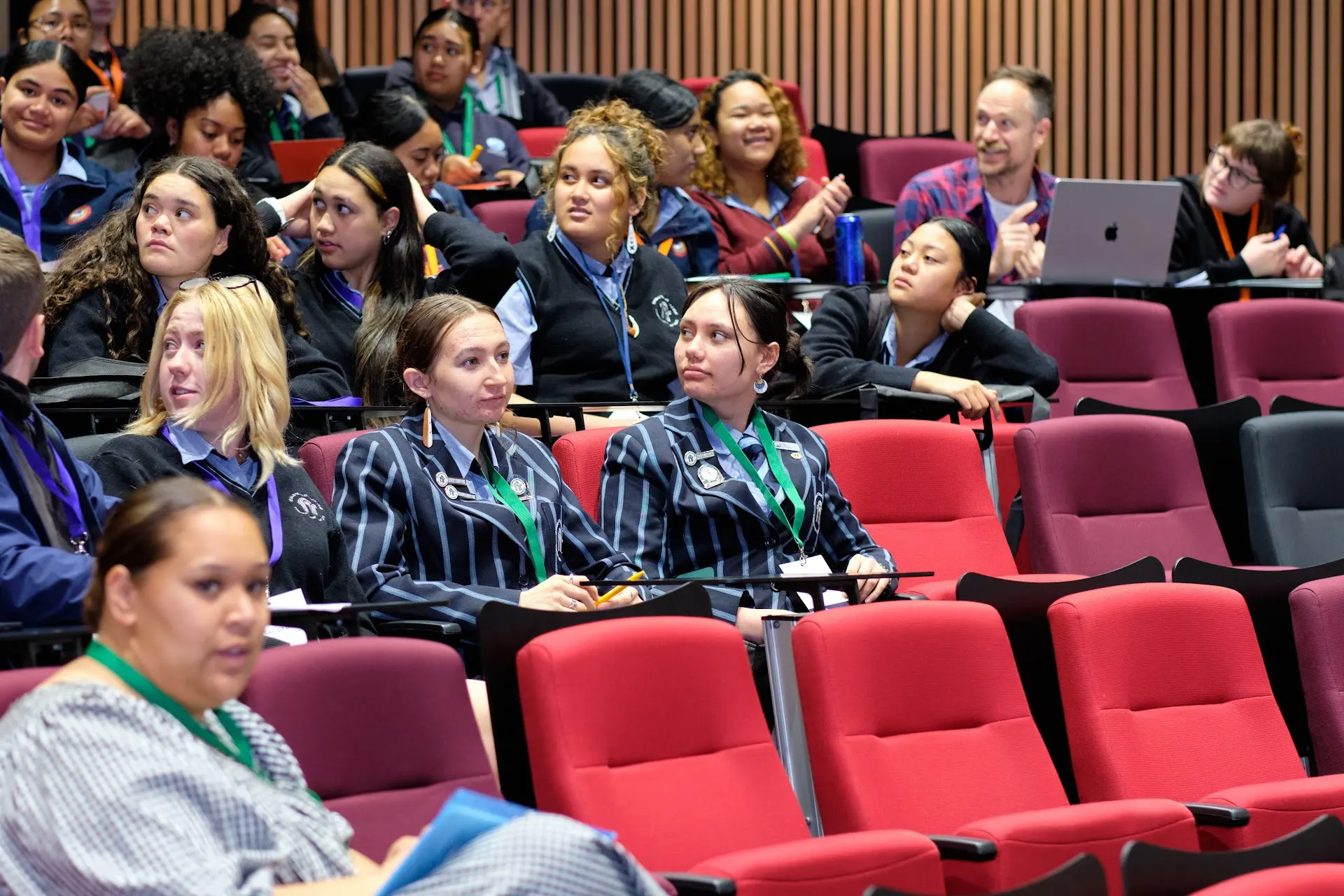 Young attendees seated in red theatre seats, listening attentively during the She Sharp Inspire Her event.