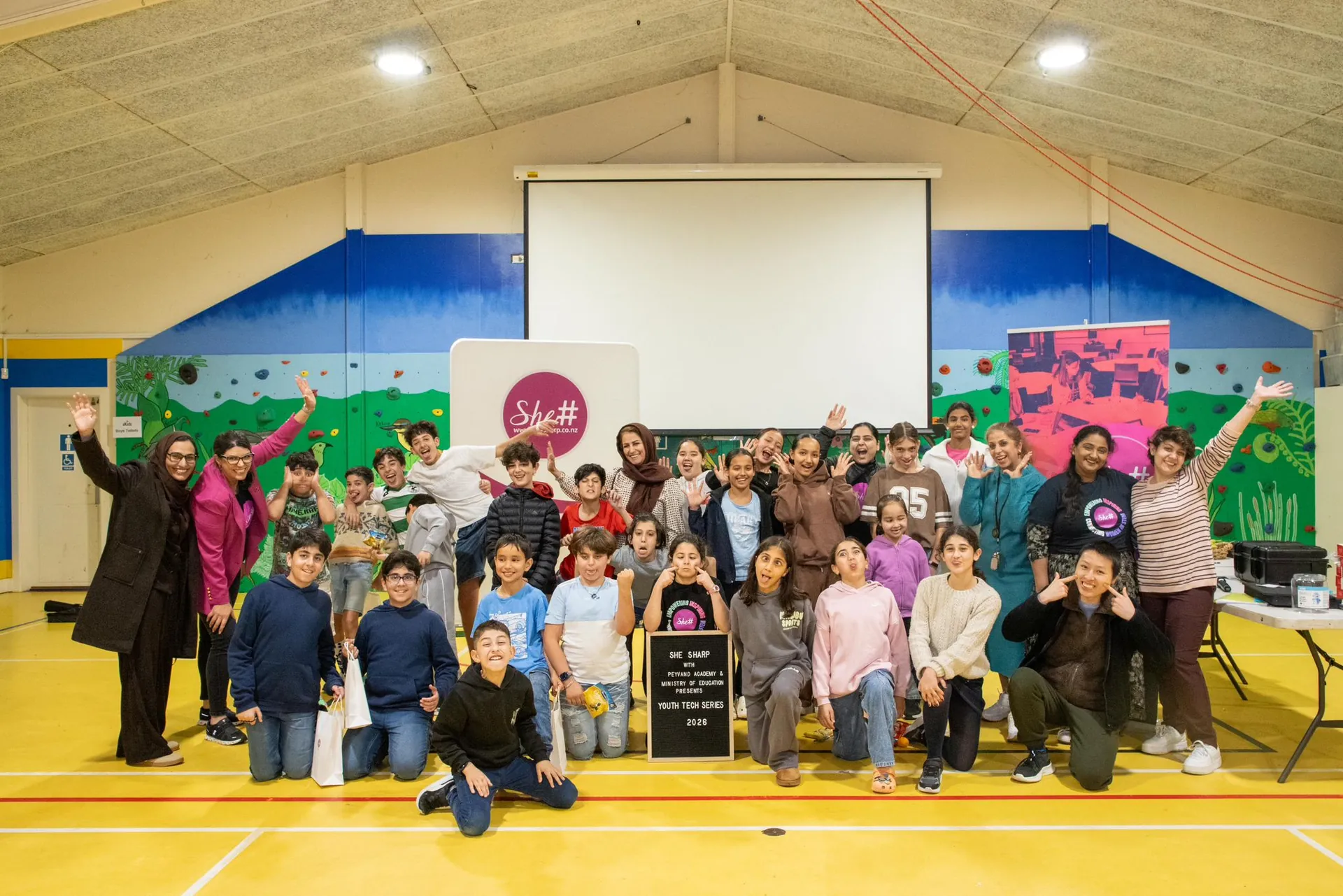 Workshop participants and SheSharp facilitators gather for a group photo with the SheSharp sign at the Youth Tech Series AI & Electronics Workshop
